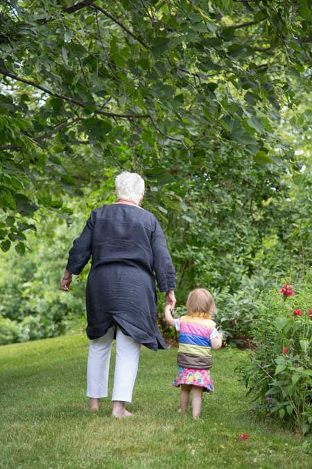 white haired woman walking , holding the hand of a toddler